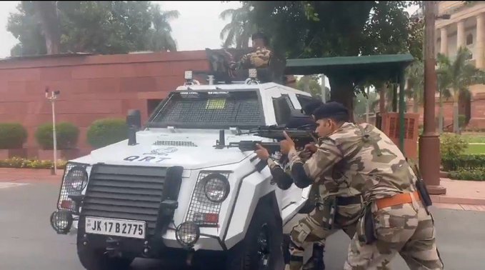 Personnel aiming rifles over an armoured quick-response vehicle near the Parliament complex